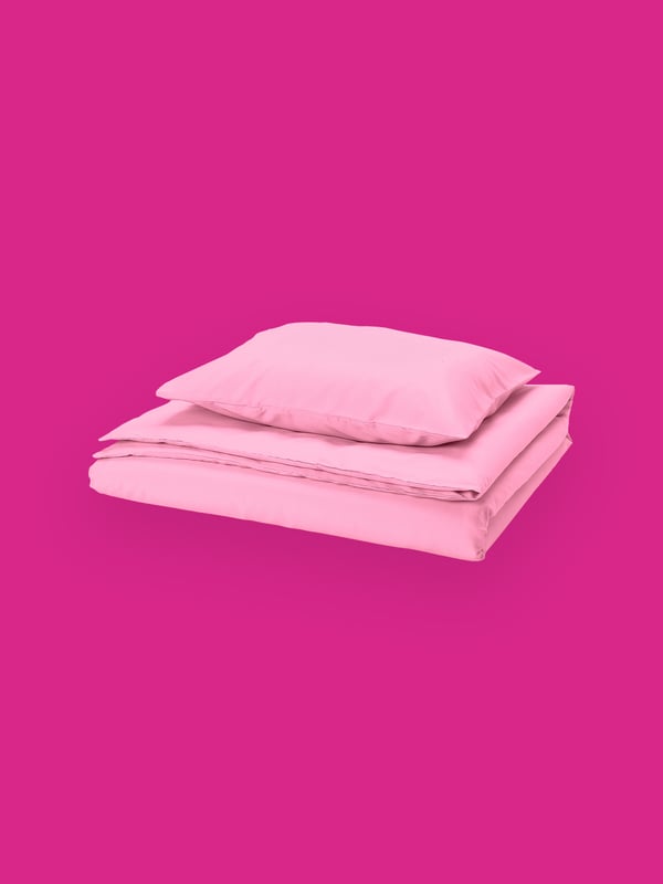 An image of a quilt and pillow stacked on top of each other from IKEA in light pink with a strong pink background.