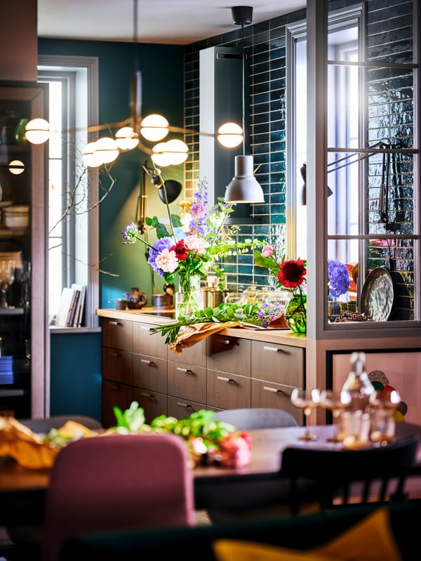A STORSLINGA LED 8-armed chandelier illuminating a dining area with a SINARP kitchen in the background.