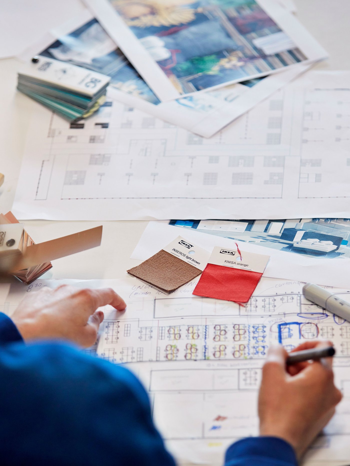 Textil mintákat mutatva tervez egy IKEA munkatárs az asztalon.