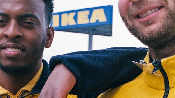 Two IKEA co-workers stand side by side, wearing company uniforms, representing IKEA for the World Refugee Day campaign.