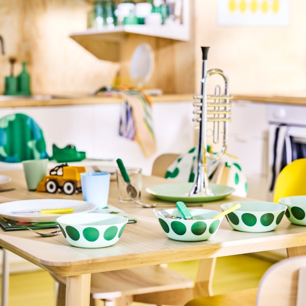 OFTAST bowls with a green stain motif on the family dining table in a Scandinavian modern kitchen.