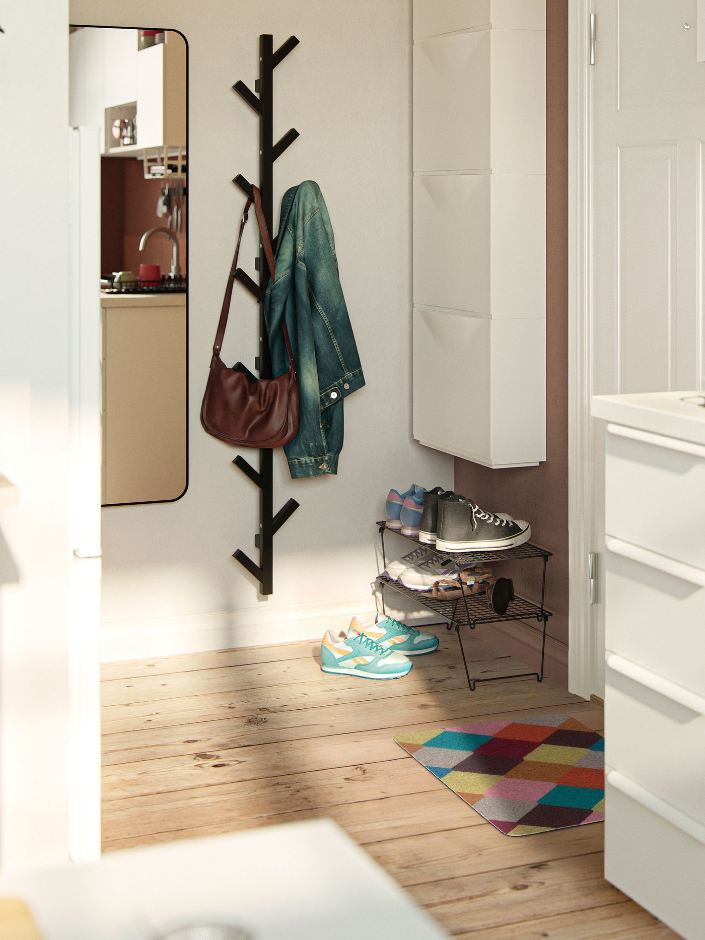 IKEA-gestylde hal met houten vloer, een zwarte wandkapstok in tak‑stijl, een smal schoenenrek met sneakers, een langwerpige spiegel, witte wandopbergruimte en een kleurrijk ruitpatroon vloerkleed.