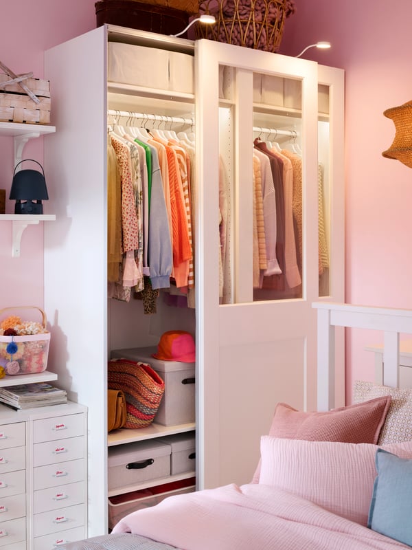 PAX wardrobe with sliding partial glass doors and light both inside and outside. One door open to show the neat order inside.