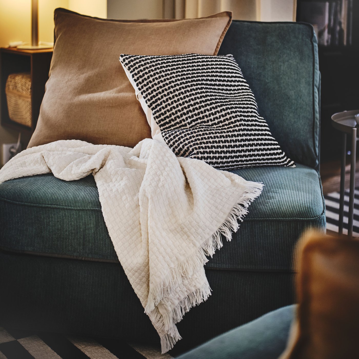 1-sits KIVIK bäddsoffa i blått med beige och svartvit prydnadskudde. 