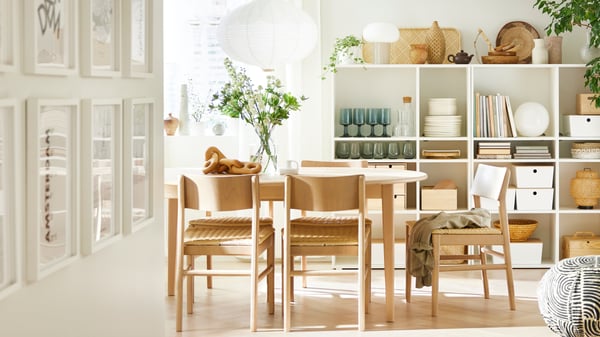 A light beech/veneer SKANSNÄS round extendable table and SKANSNÄS light beech chairs stand in a room with a wooden floor.