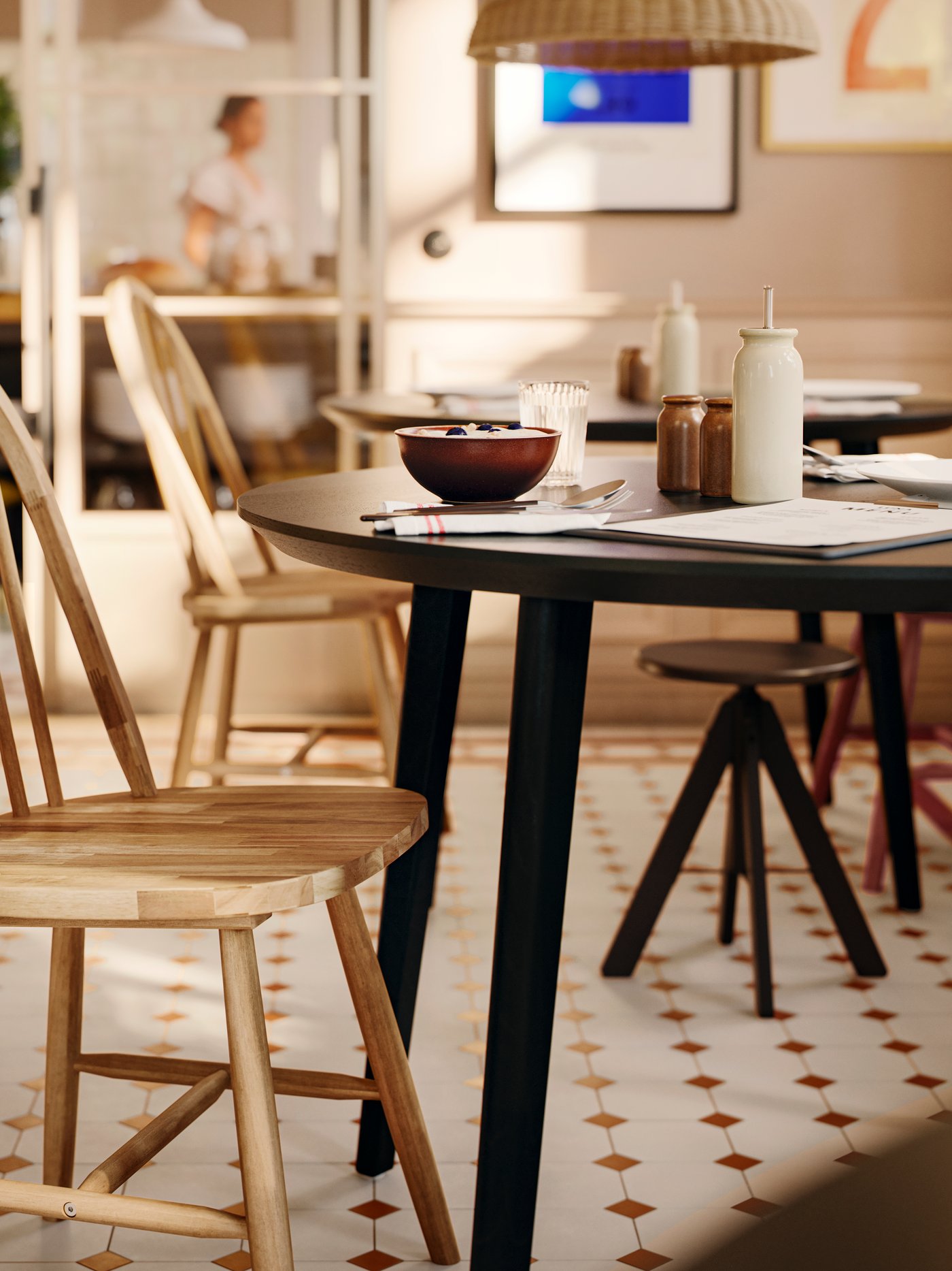 A solid acacia SKOGSTA chair with an arched backrest and spindles next to a dark round table in a commercial dining area.