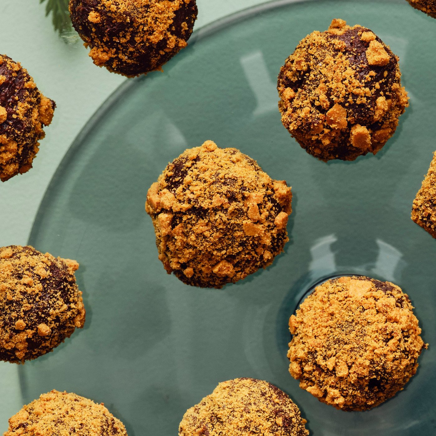 Primo piano di un vassoio di vetro pieno di tartufi al cioccolato fondente con biscotti allo zenzero, ricoperti di granella.