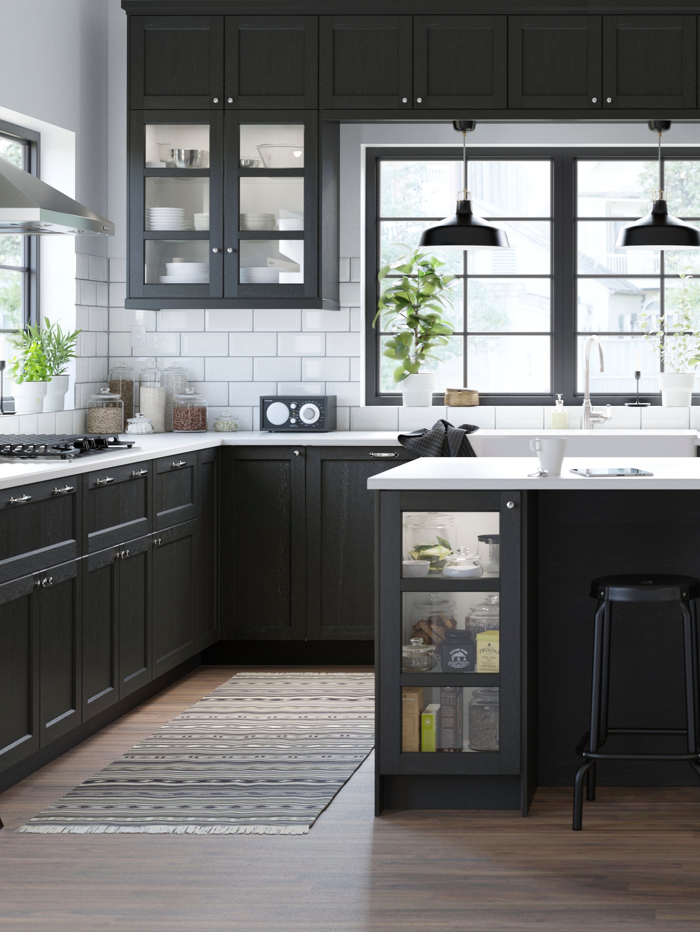 Et stort, sort køkken med en køkkenø med hvid bordplade og hvide vægfliser mellem vinduer, overskabe og underskabe.