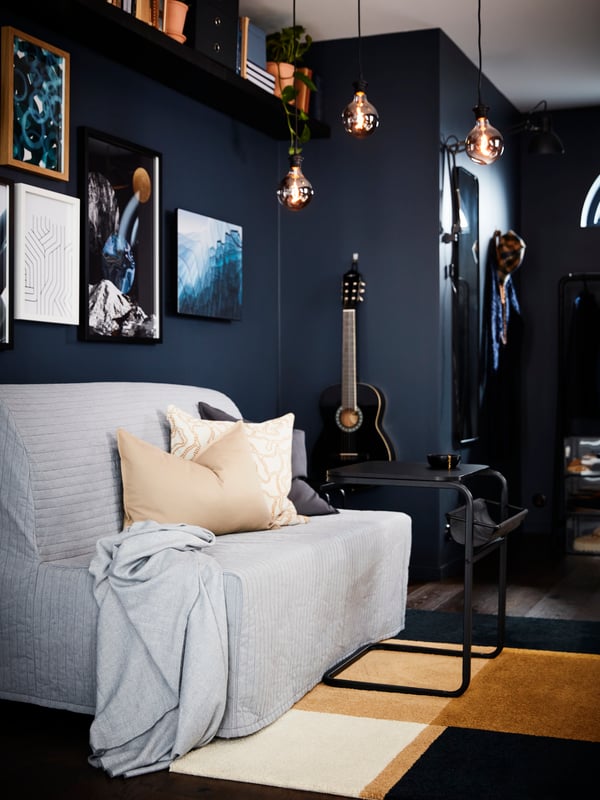 Three globe grey clear glass MOLNART LED bulbs hang from the ceiling above a LYCKSELE LÖVÅS sofa-bed and a rug.