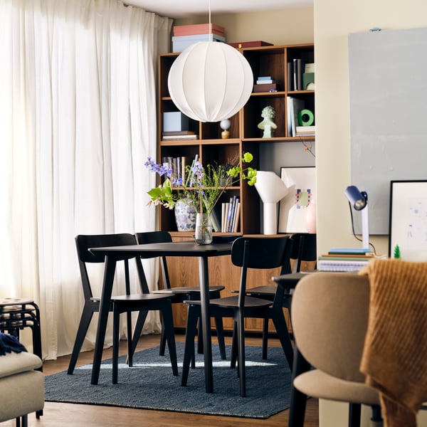 A dining area with a LISABO table and LISABO chairs, a lamp hanging above the table and blue LANDBANA rug on the floor.