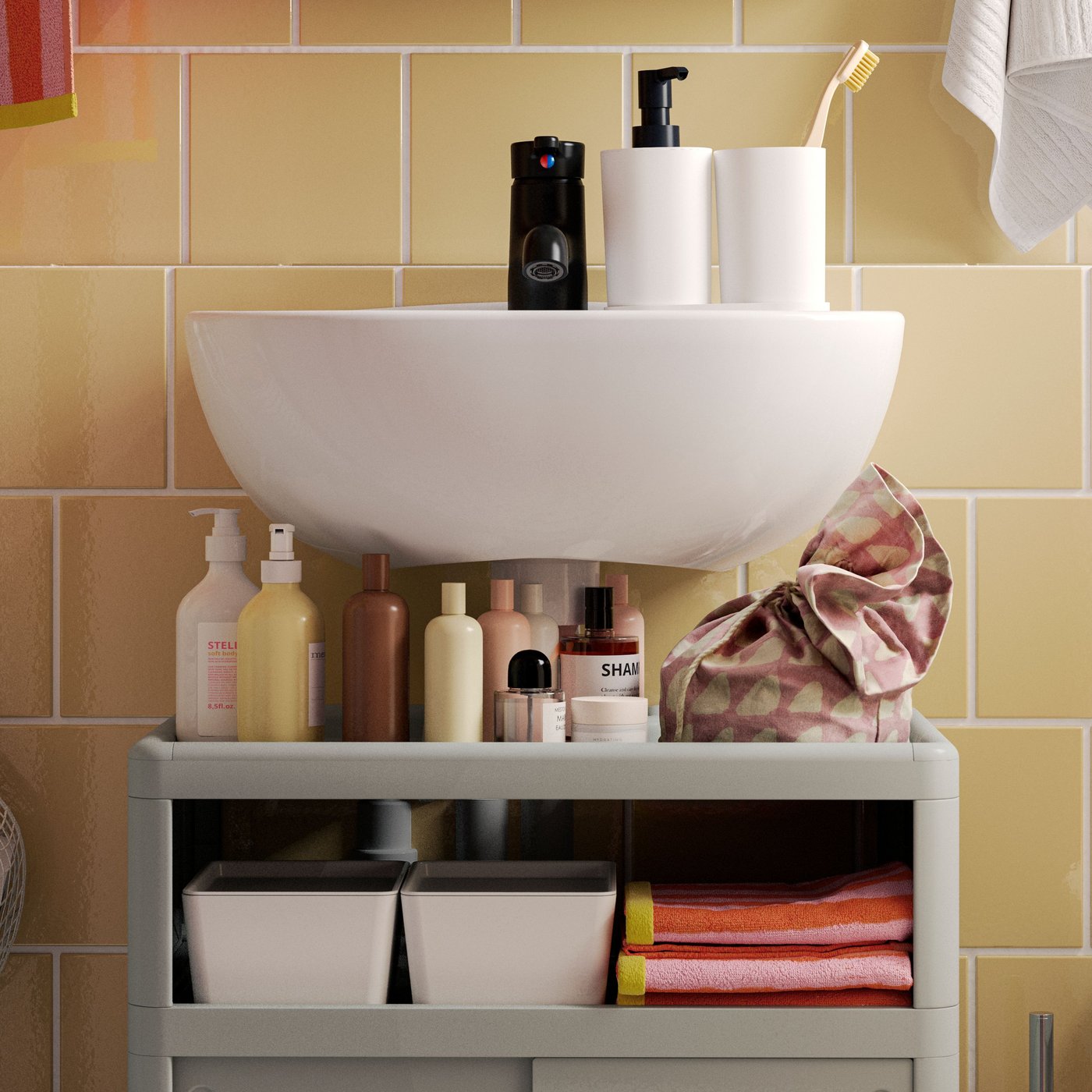 A white SKATSJÖN single wash-basin is mounted above a green IVÖSJÖN wash-basin base cabinet with bathroom products on it.