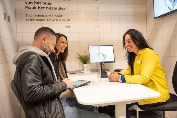 Twee klanten zitten bij IKEA medewerker om hun ideale keuken te ontwerpen.