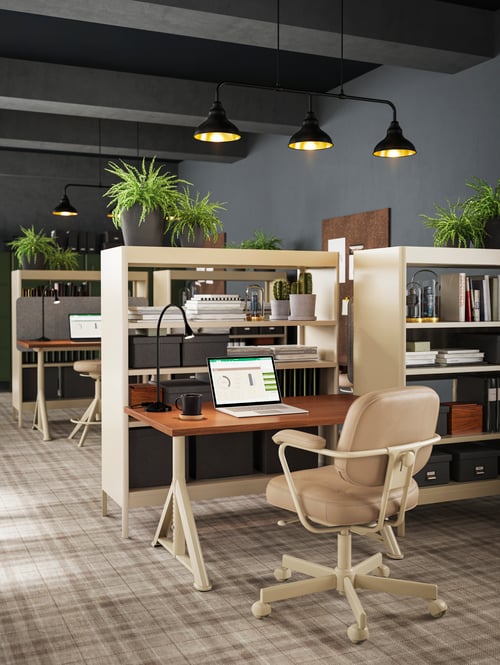 A modern office that features beige shelving units, a beige office chair, a rectangular chair, and a LED work lamp.