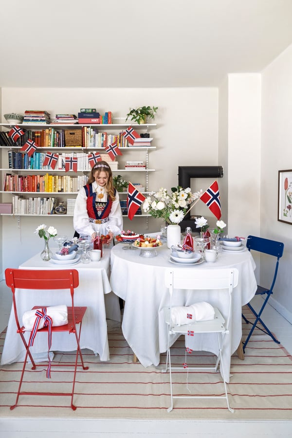 En bunadskledd jente dekker bordet til 17. mai.