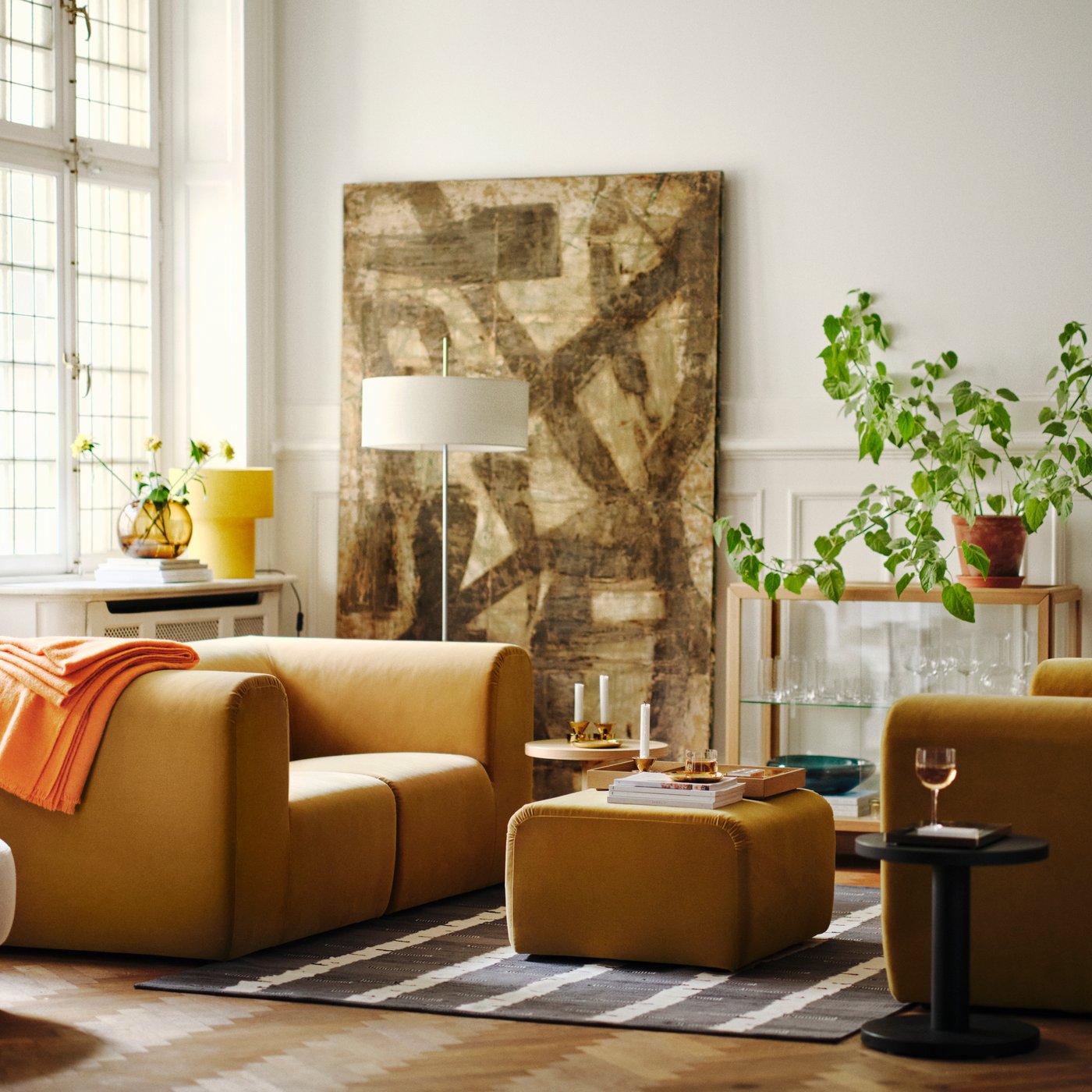 Un salon lumineux avec deux canapés 2 places STOCKHOLM 2025 beiges placés face à face, avec un pouf sur un tapis entre les deux.