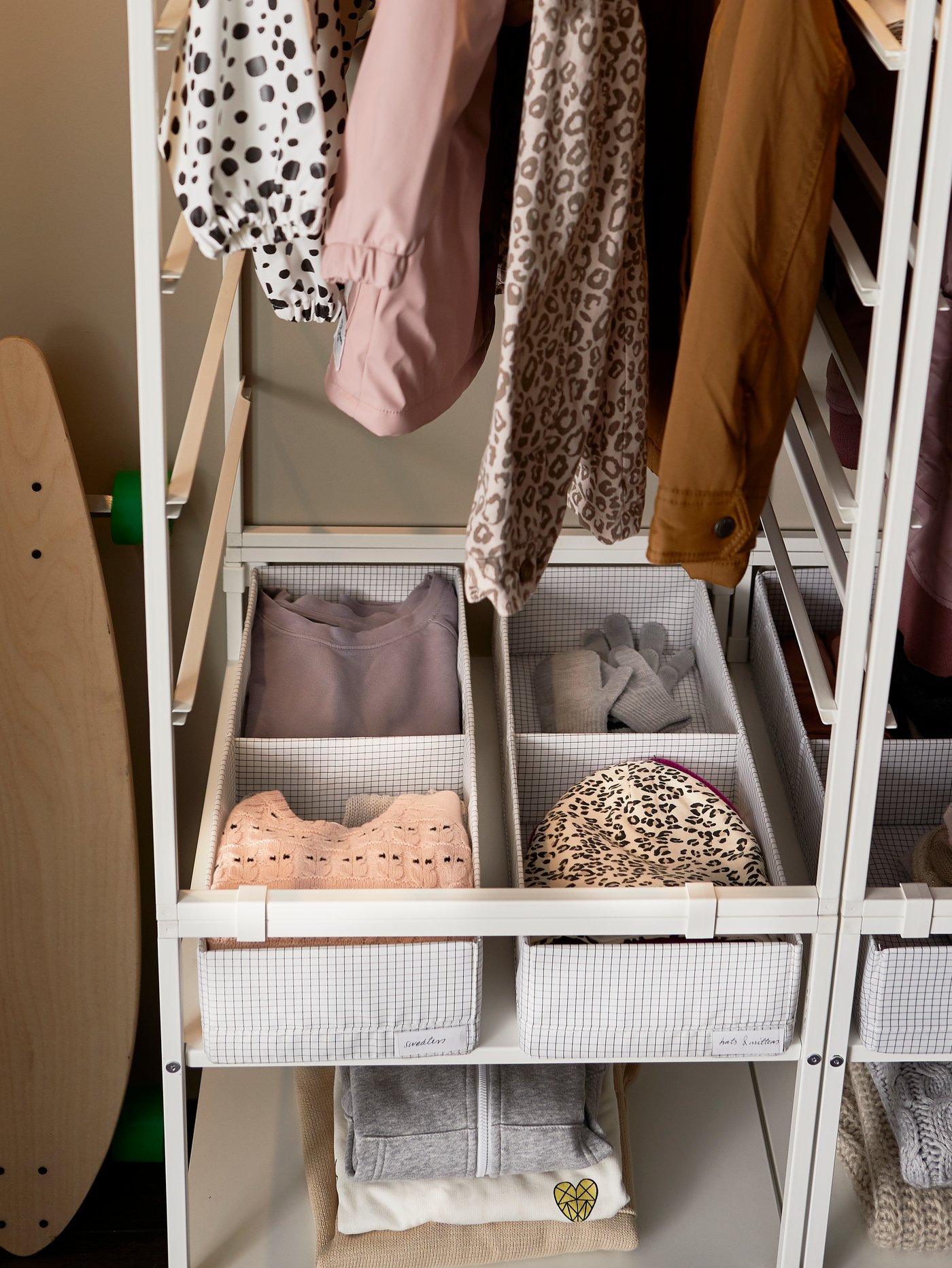 衣類が収納されたSTUK/ストゥーク ボックス 仕切り付き。JONAXEL/ヨナクセルの収納内のシェルフに設置され、ボックスの上にはつるされた洋服が見えている。