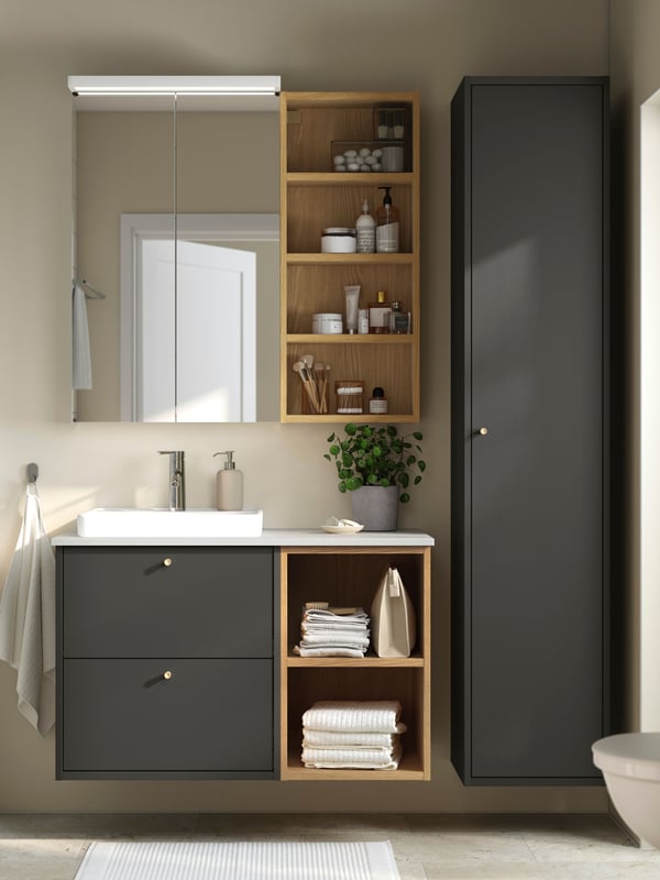 Un bany amb un moble de lavabo amb dues portes HAVBÄCK de color fosc, un lavabo ORRSJÖN blanc i un mirall en vertical.