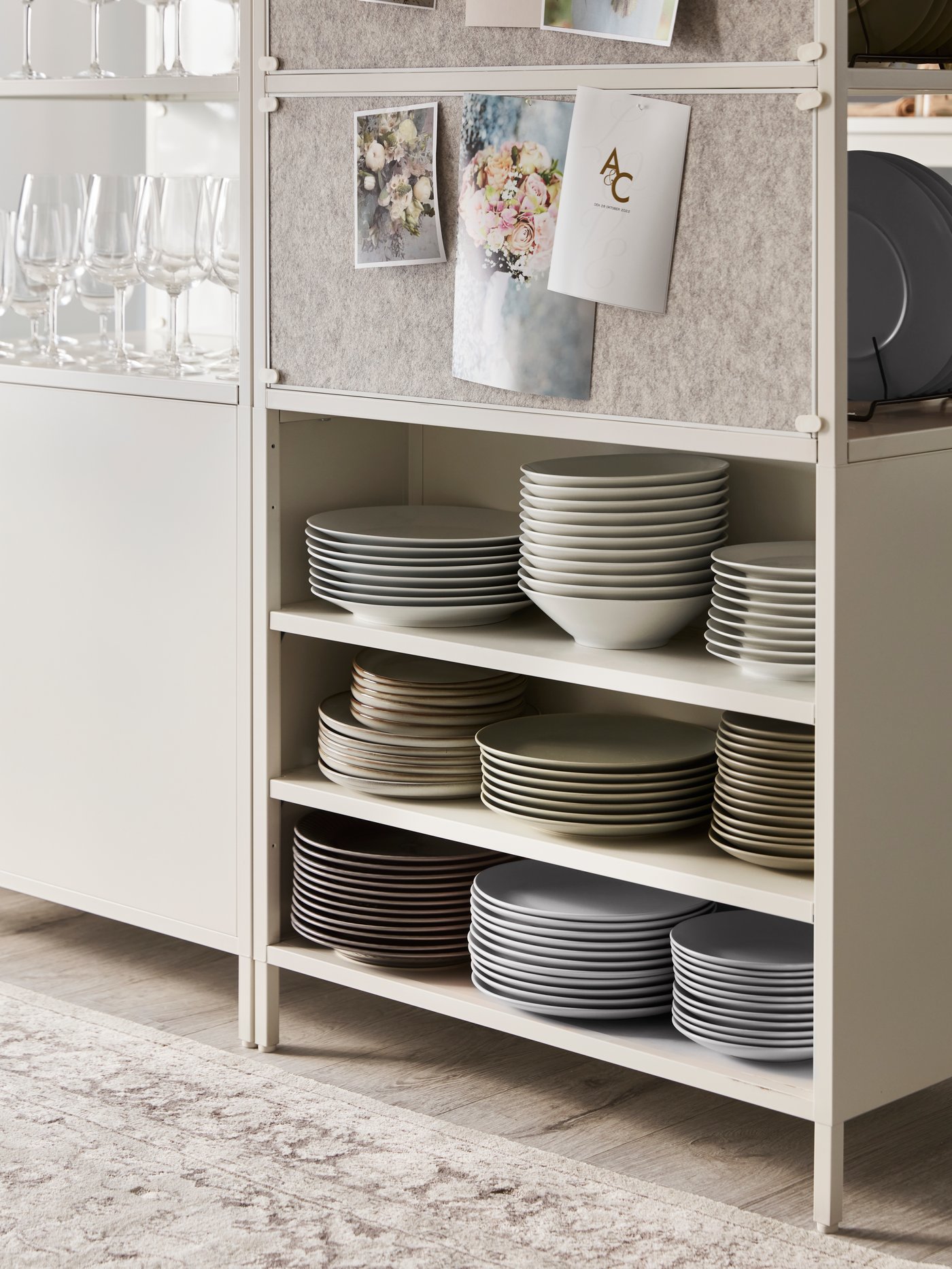 Zona de la cocina con un armario blanco de puertas correderas, con varias pilas de platos en los estantes.