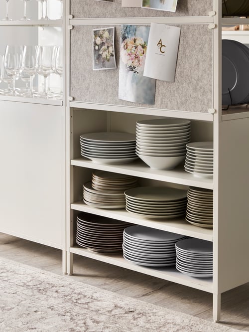 Kitchen area featuring a white cabinet with sliding doors, with multiple stacks of plates on the shelves.