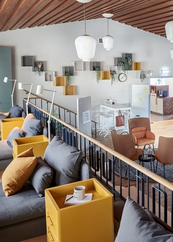 Öppen och modern kontorsmiljö med loungedel på loftet inredd med grå SÖDERHAMN schäslonger och hula hurtsar.Nedanför räcket syns kontors och mötesyta. 
