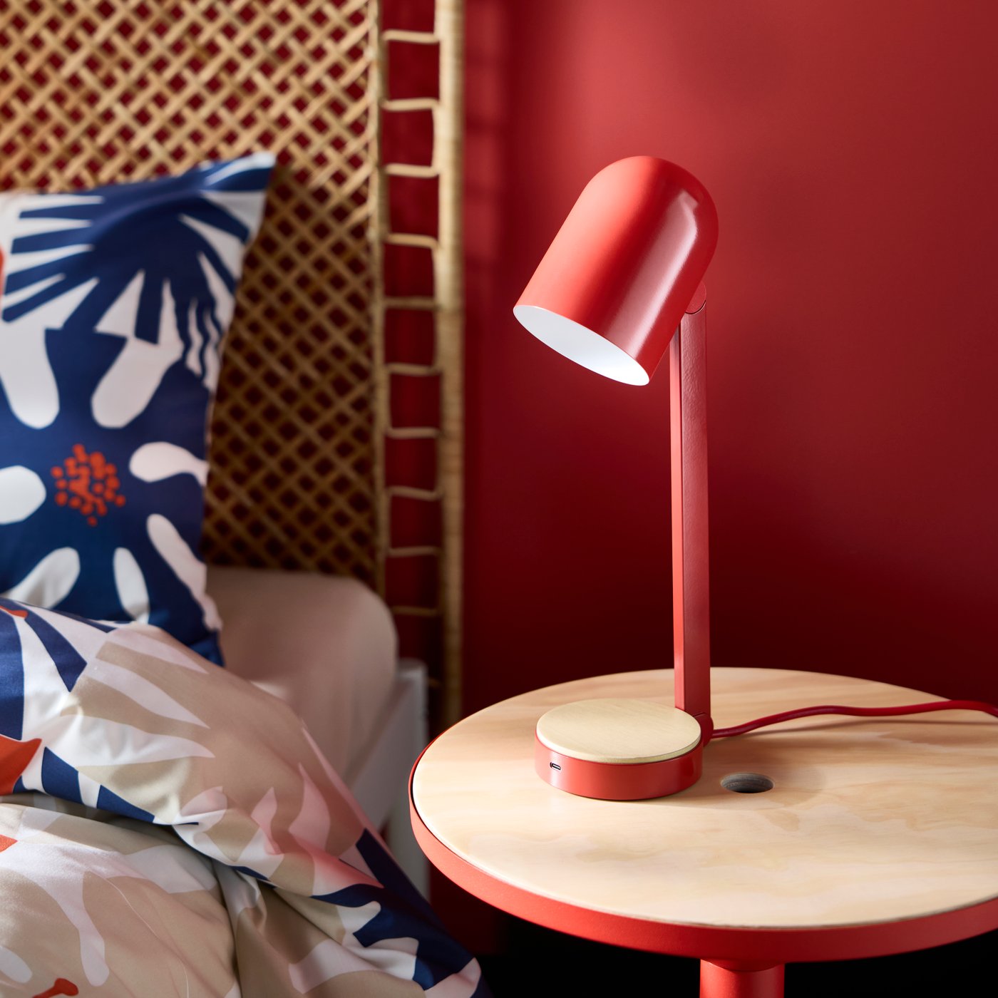 A white DVALA sheet in the bedroom and red ENSMÄRKE desk lamp on red bedside table in the bedroom