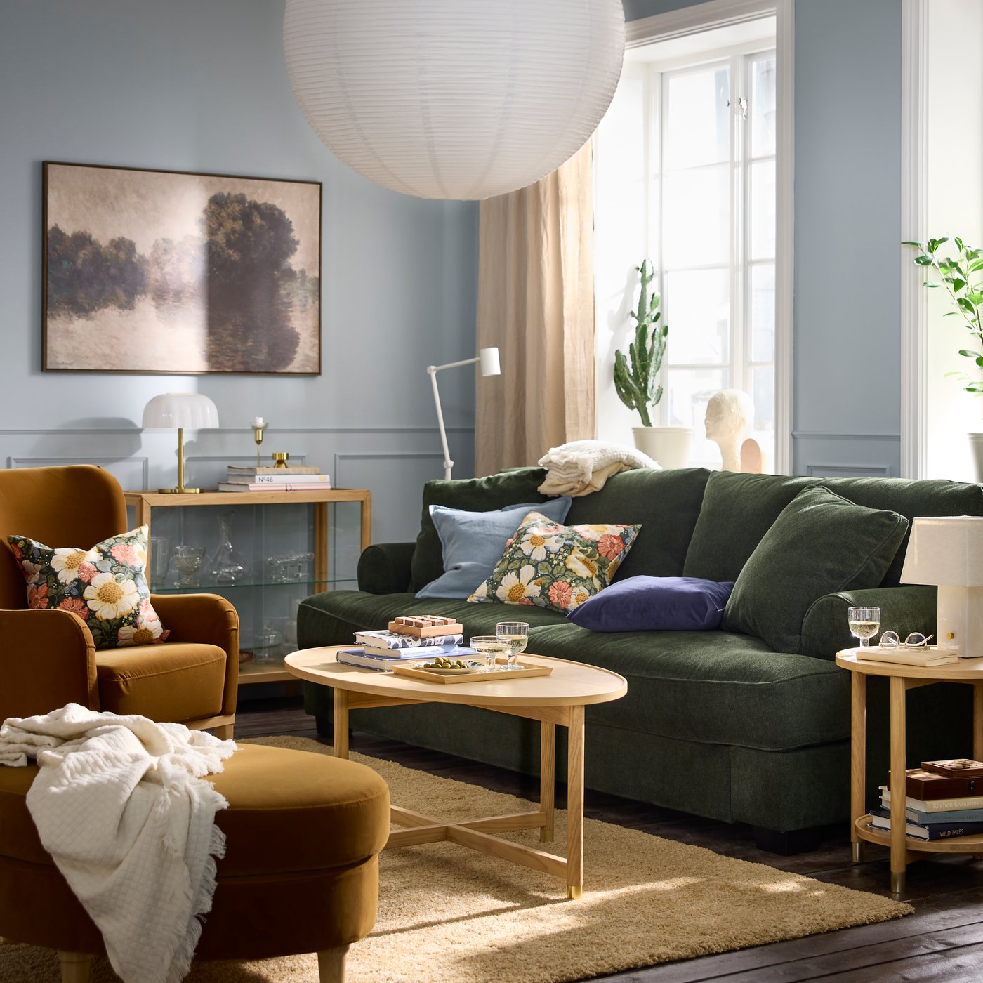 A softly sunlit, colourful living room with a VALNÄS sofa, floral-pattern cushions, a VALNÄS footstool, and a coffee table.