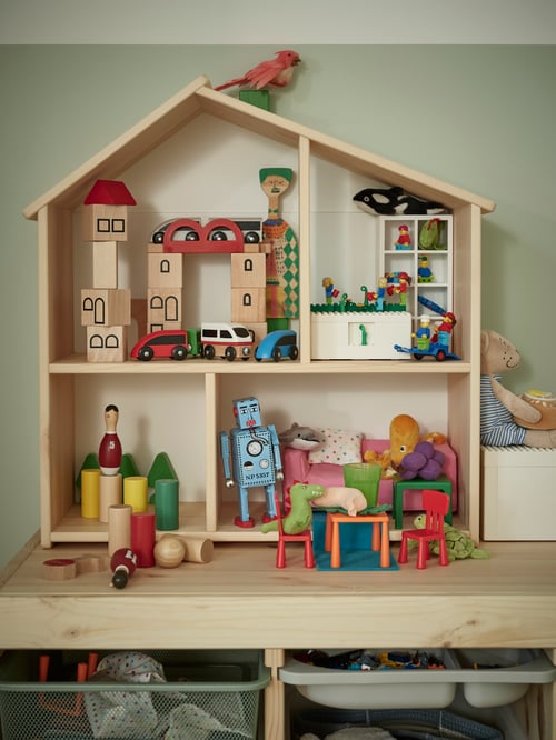 Modernes Kinderzimmer mit einem FLISAT Puppenhaus/Wandregal, u. a. mit einer BYGGLEG LEGO®-Schachtel mit Deckel, HUSET Puppenmöbeln Schlafzimmer und UNDERHÅLLA Holzbauklötzen.