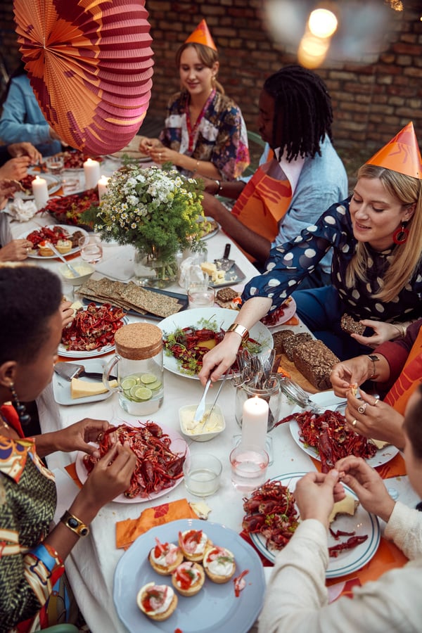 A group of friends sitting at a dining table in a backyard enjoying a crayfish feast.