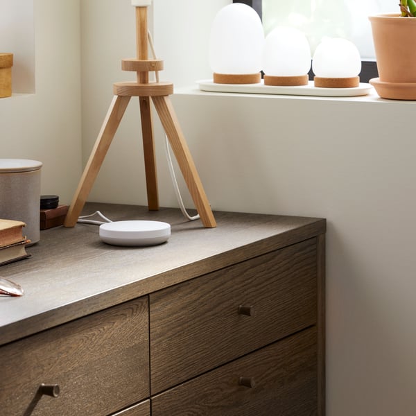 A close-up of the top corner of TONSTAD chest of six drawers in oak veneer, standing in a corner below a window.