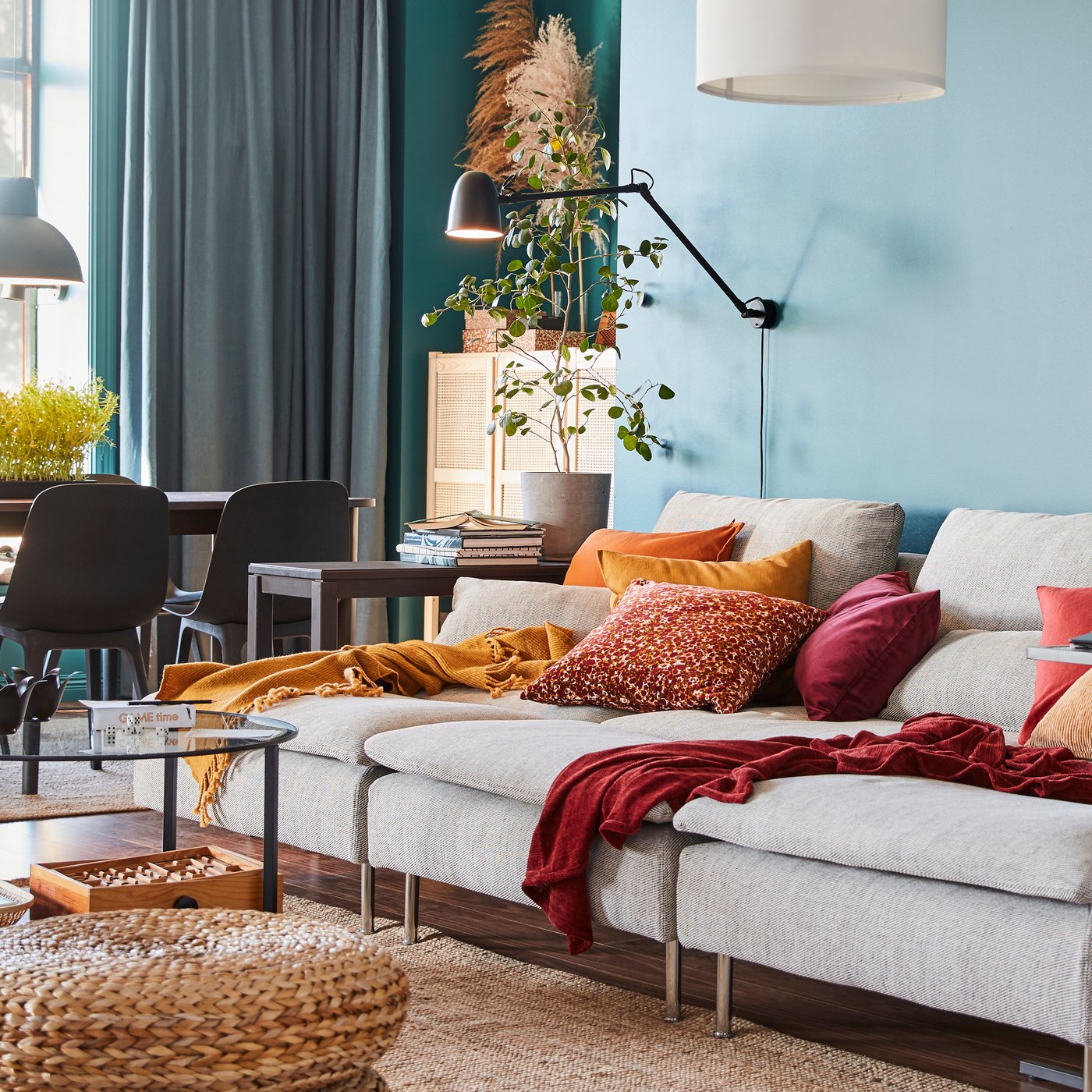 A SKURUP work/wall lamp is mounted on the wall above three SÖDERHAMN chaise longues in a colourful living room.