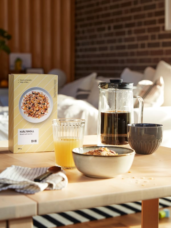 Leckeres Frühstück auf einem Wohnzimmertisch, u. a. mit Saft, einer Kaffeekanne und dem HJÄLTEROLL Müsli.