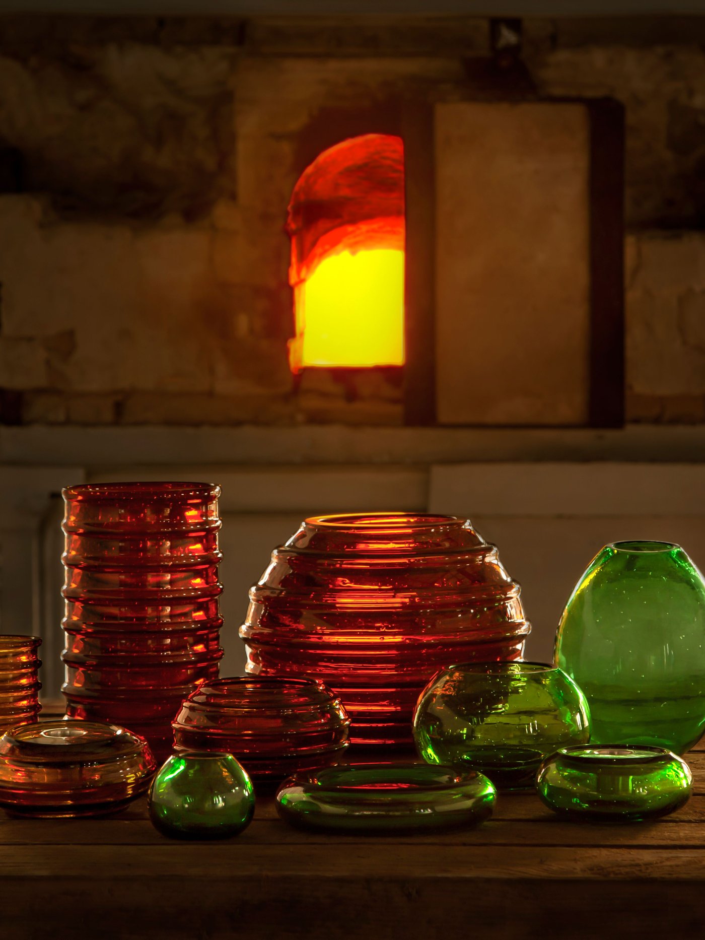 HÄNGBJÖRK Vasen und Kerzenständer sind in der Fabrik vor einem Glasschmelzofen zu sehen.