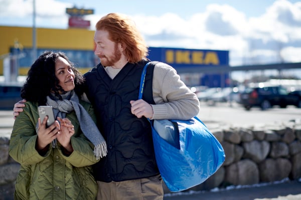 A couple with a blue IKEA bag in front of an IKEA store