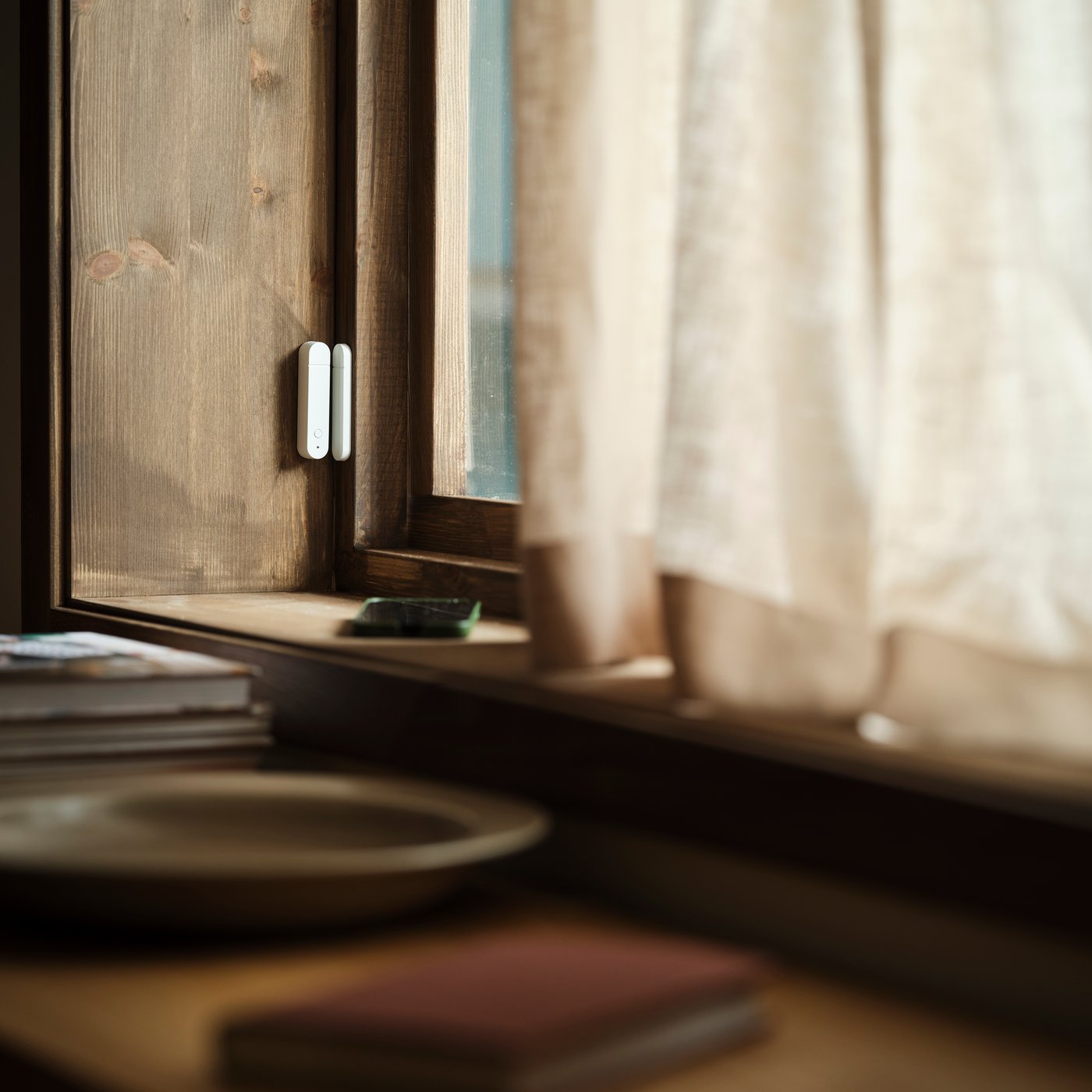 A MYGGBETT door/window sensor is mounted on a window and on the frame of a window. The window is closed.