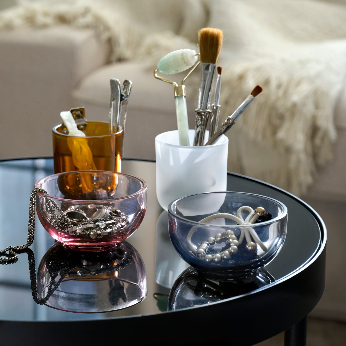 Deux photophores TALLTITA séparés pour former quatre éléments individuels, posés sur une table d’appoint et remplis d’accessoires de beauté.