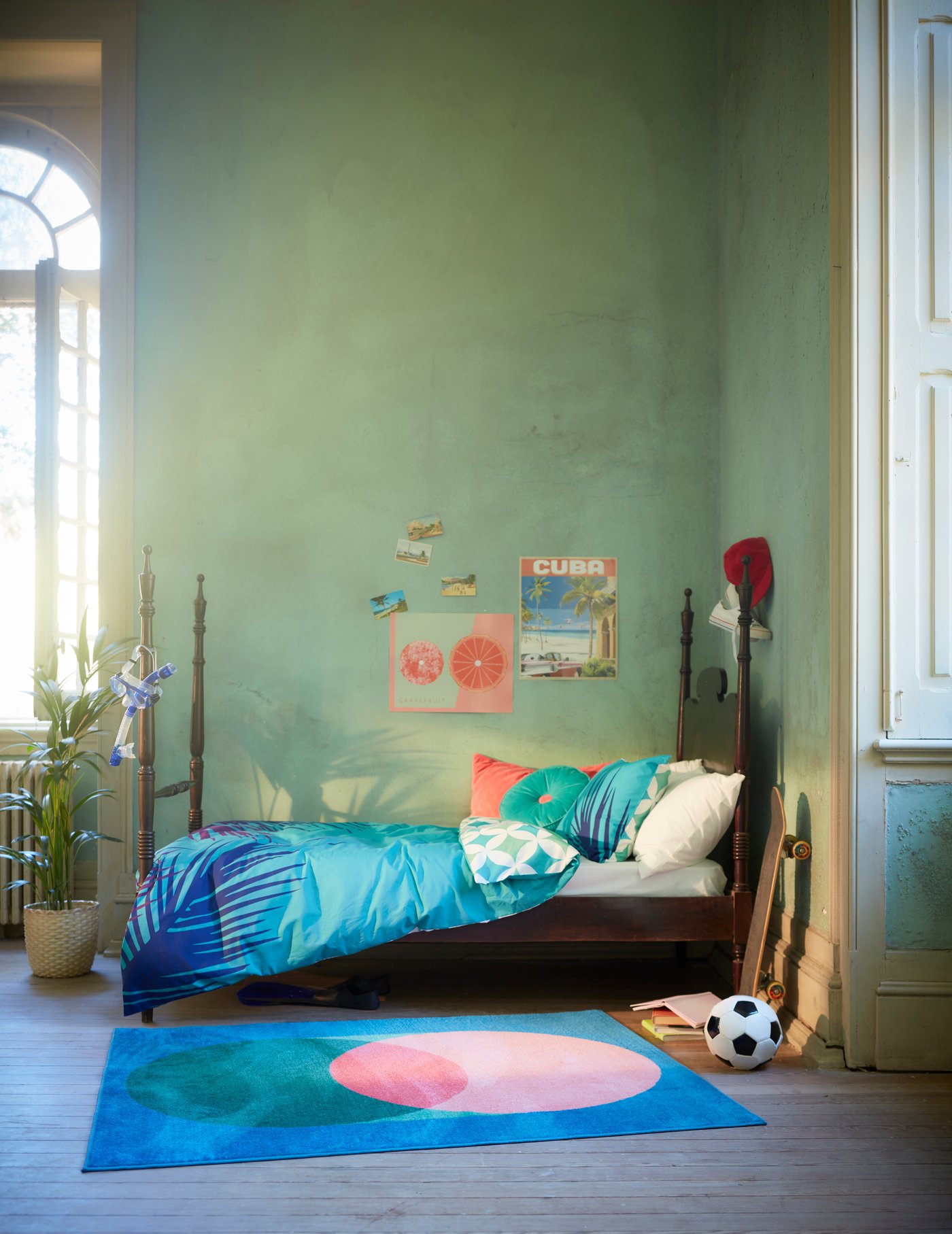 Una camera da letto Scandi-boho per bambini con tessuti in tonalità di blu e un tappeto colorato con giocattoli sul pavimento.