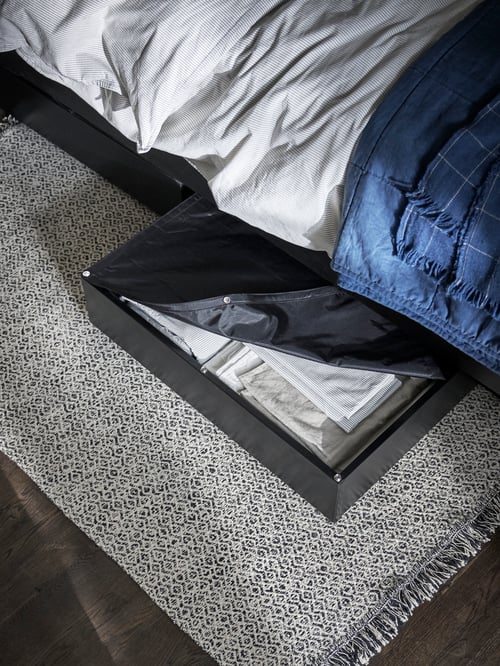 Bedroom with VINDUM rug, VARDÖ bed storage box with clothes and open lid bed frame, and GULVED bedspread.