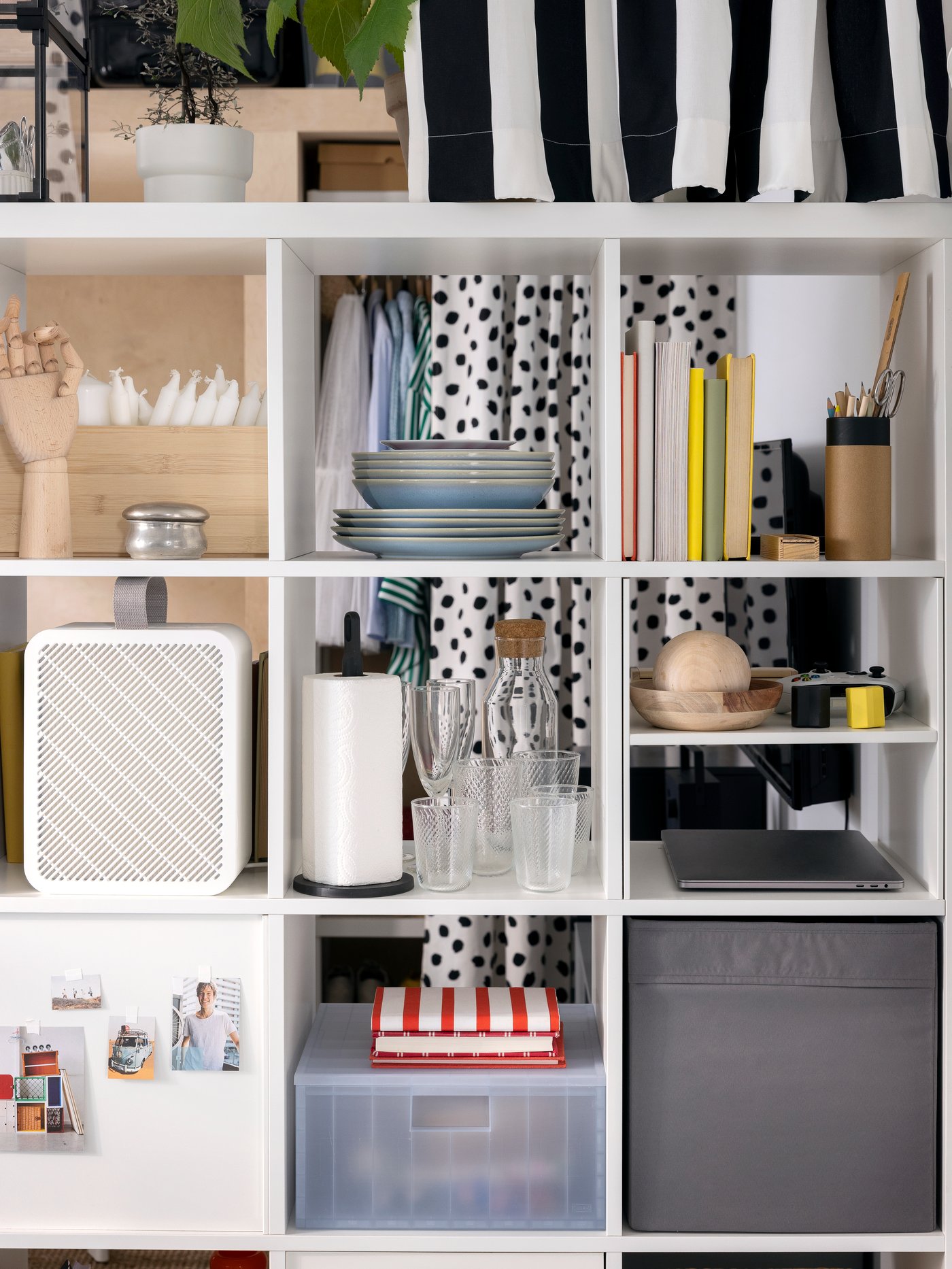 Objects including an UPPÅTVIND air purifier and storage boxes stand on the shelves of a white KALLAX shelving unit.