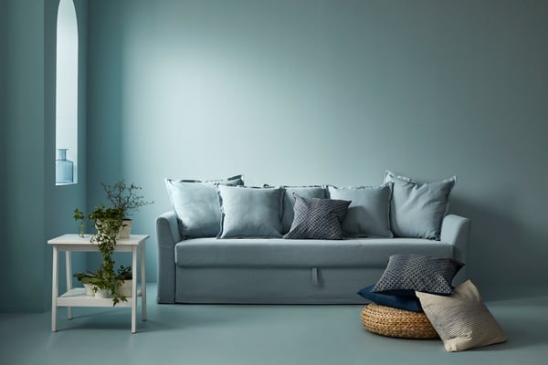 En lyseblå HOLMSUND sovesofa i et lyseblåt rum.
