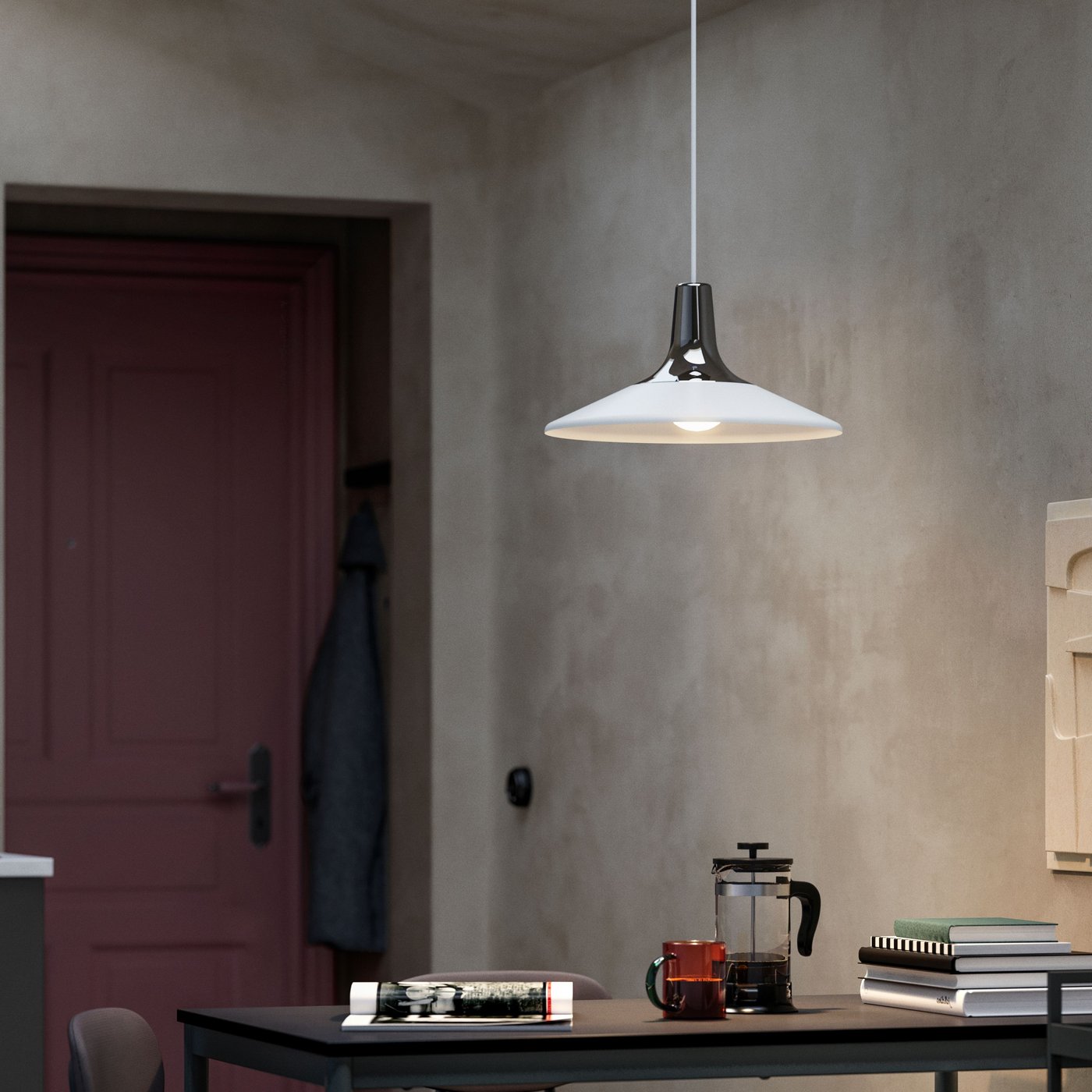 Matsal med svart bord, böcker och kaffepress under en vit FYRTIOFYRA pendellampa med metalltopp, mot grå vägg och röd dörr i bakgrunden.
