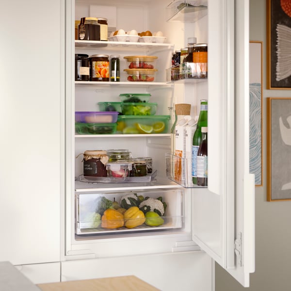A SUPERKALL fridge/freezer combo with the door open to display lots of food, bottles and PRUTA sandwich containers stored.