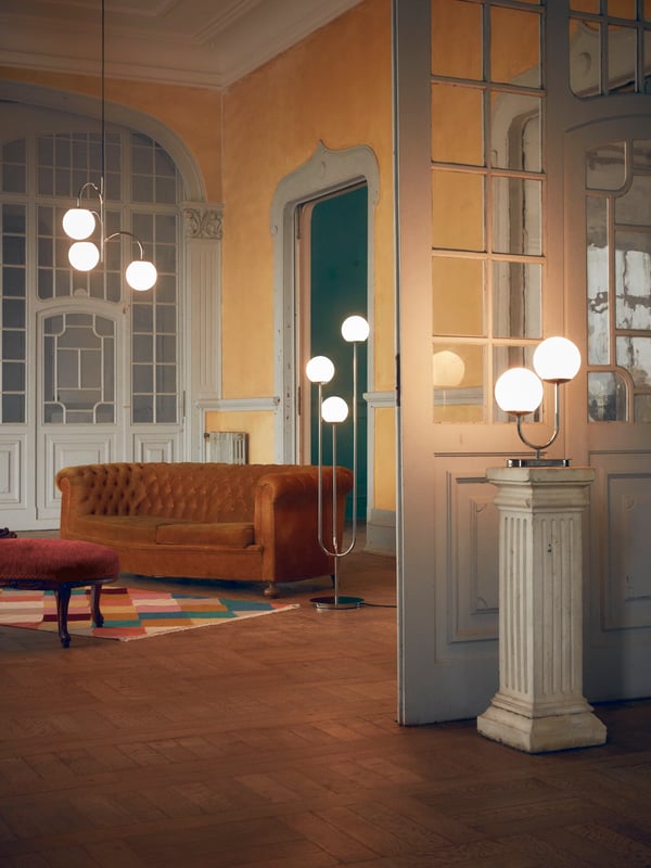 A grand room showing three SIMRISHAMN lamps – a pendant, floor and table lamp with their glass domes lit up.
