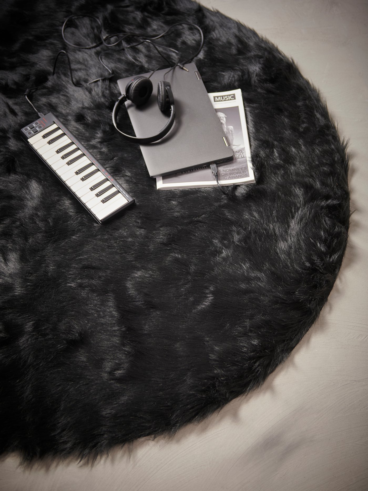 A black OBEGRÄNSAD record bag with vinyls inside sitting on a wooden floor next to shelves of records and a white curtain.