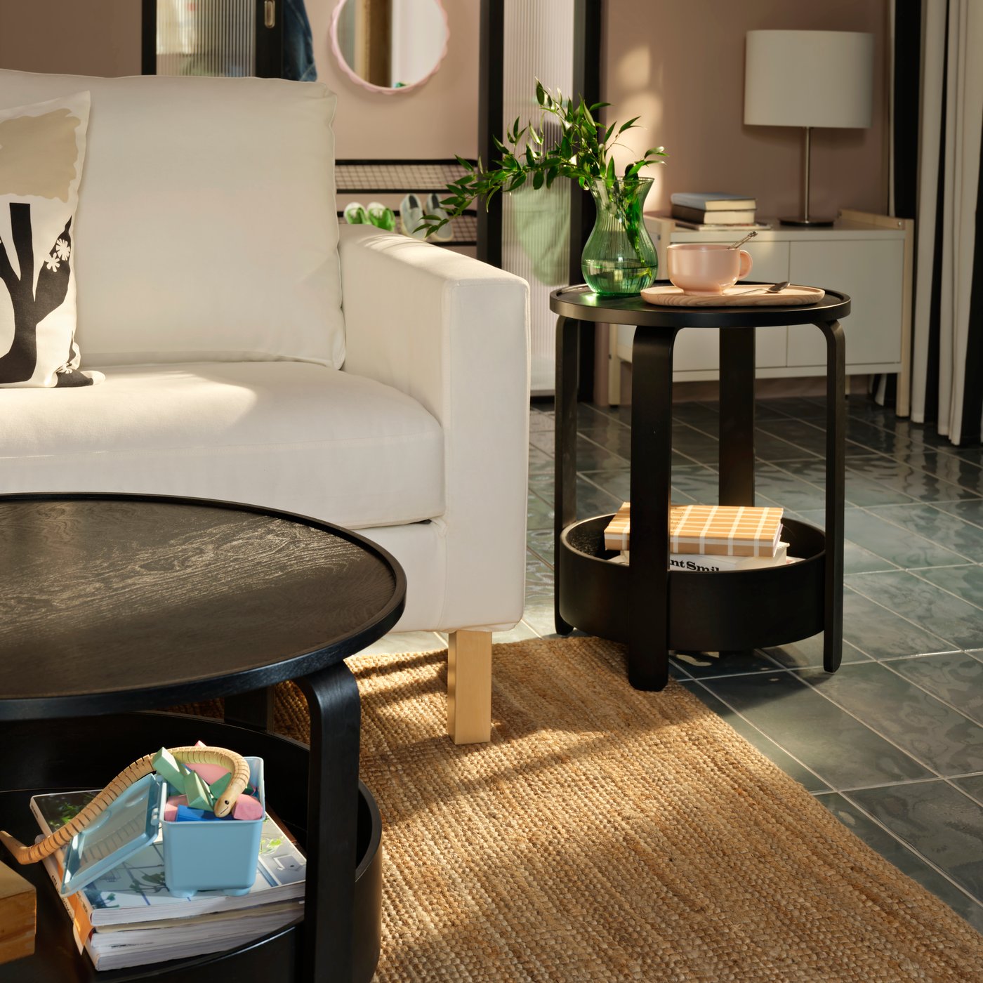 A light living room with a black BORGEBY side table and coffee table, both placed near a white SALTSJÖBADEN two-seat sofa.