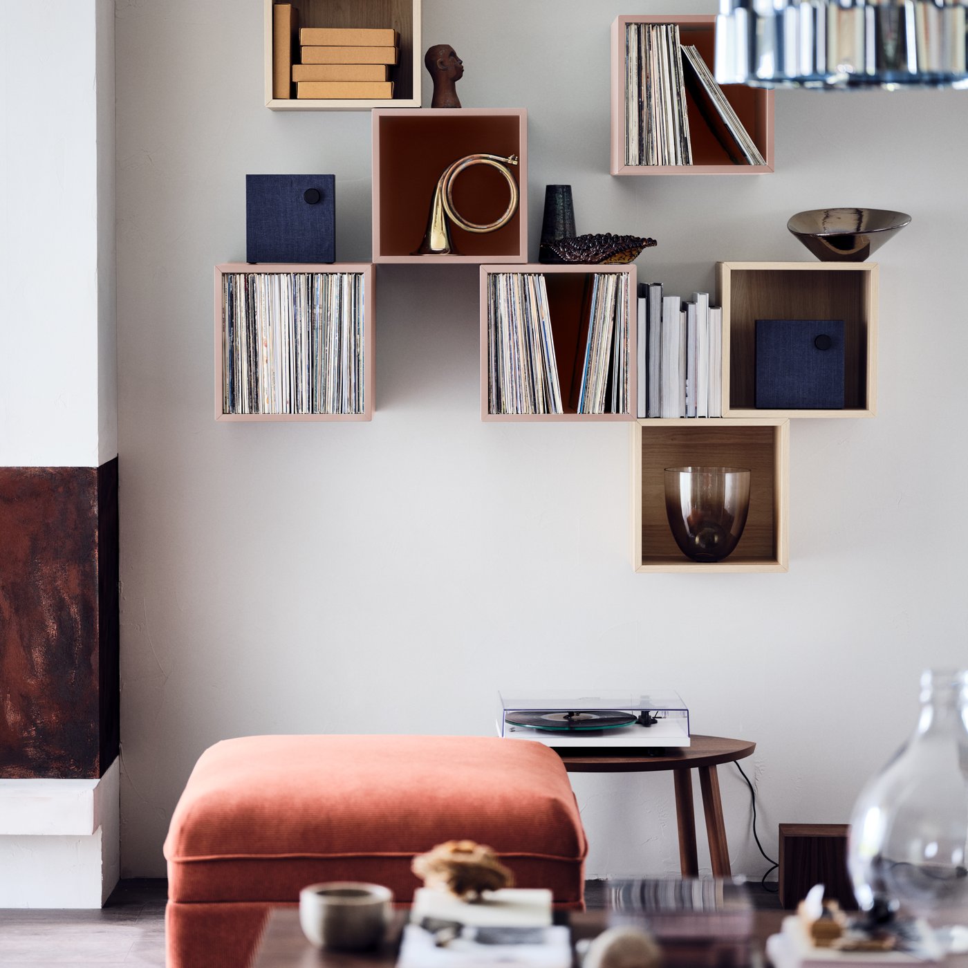 Flera kubformade EKET skåp i olika färger i en formation på väggen i ett rum i retrostil.