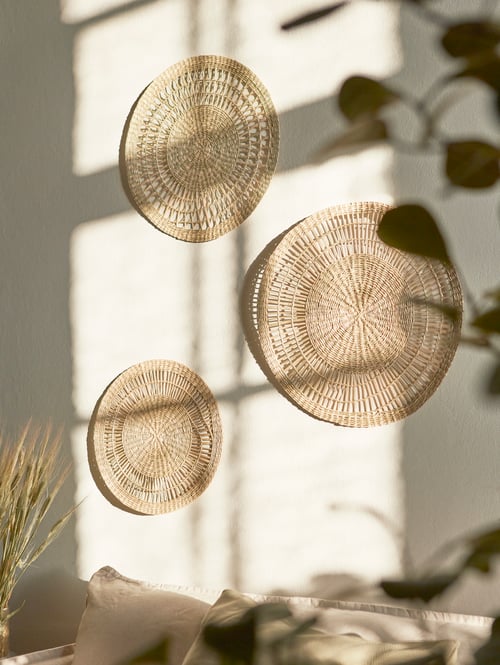 Focused shot of a set of three round wall decorations hanging on a wall with multiple pillows placed underneath.