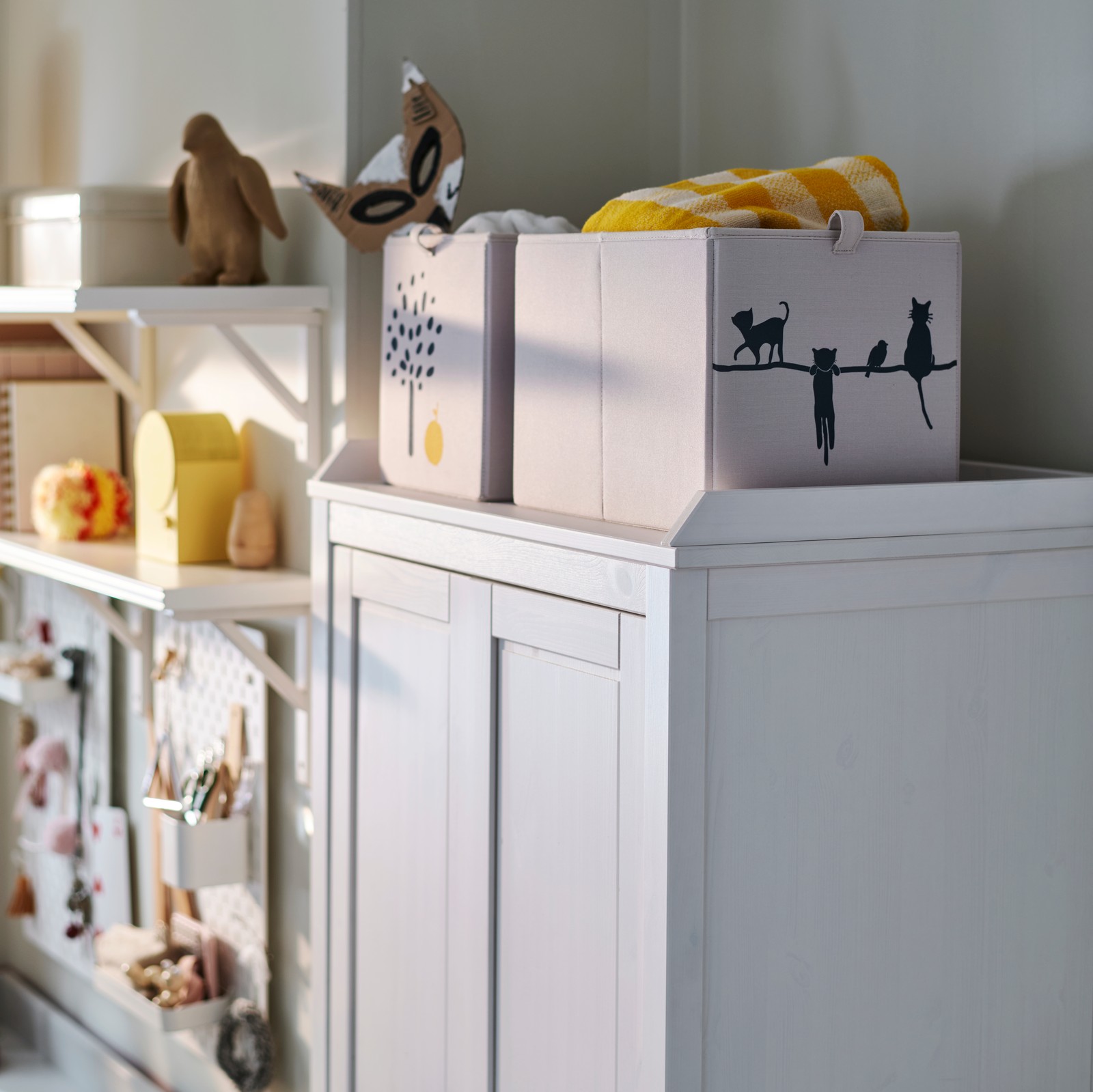 A beige BARNDRÖM box displayed on top of a white SUNDVIK wardrobe, surrounded by decorative items and a cosy atmosphere.