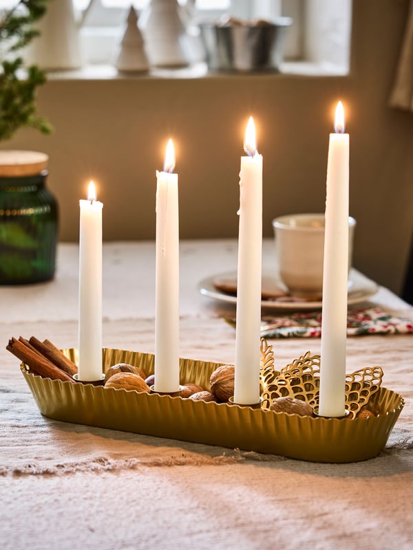 Adventsljusstake i guld med levande ljus.