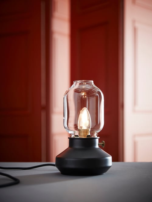 Une lampe de table conçue pour ressembler à une lampe à l'ancienne, avec une ampoule qui ressemble à la flamme d'une bougie.