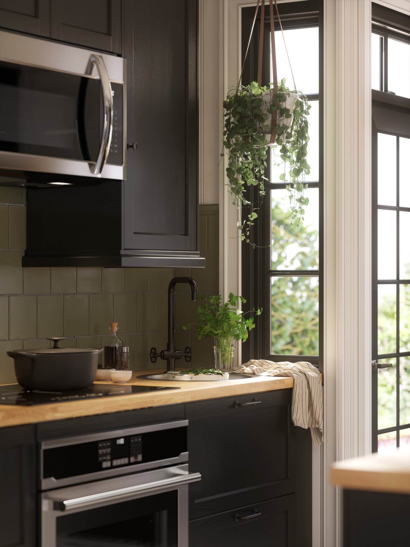 เครื่องใช้ไฟฟ้าในครัวและซิงก์พร้อมก๊อกผสมครัวสีดำถูกจัดวางไว้ในห้องครัวที่มีบานตู้ LERHYTTAN/เลียร์ฮึตตัน ย้อมสีดำ